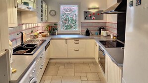 Eine kleine Küche mit eingebautem Backofen, Spüle und einem Fenster mit dekorierter Scheibe.
