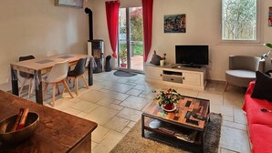 Ein modernes Wohnzimmer mit Essbereich, Fernseher und einem roten Sofa.