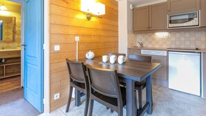 Una cocina moderna con paneles de madera, una mesa de comedor con sillas y un microondas.
