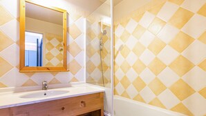 Un baño con tocador de madera, lavamanos, espejo y ducha.