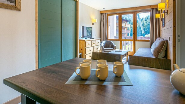 Una habitación acogedora con una mesa de madera, un sofá y un televisor.