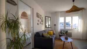 Un salon moderne avec un canapé, une table basse, une grande plante en pot et un luminaire suspendu.