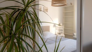 Une chambre à coucher avec un lit, une table de chevet, une lampe et une armoire blanche.