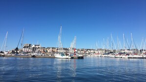 Un port de plaisance où sont amarrés de nombreux voiliers, avec une eau calme et des bâtiments en arrière-plan.