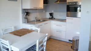 Une cuisine moderne avec des meubles blancs, un évier en acier inoxydable et une machine à café.