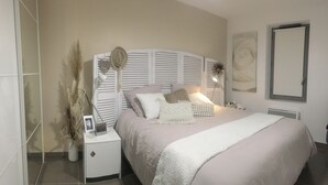 Un dormitorio con cama, mesita de noche, lámpara y objetos decorativos.