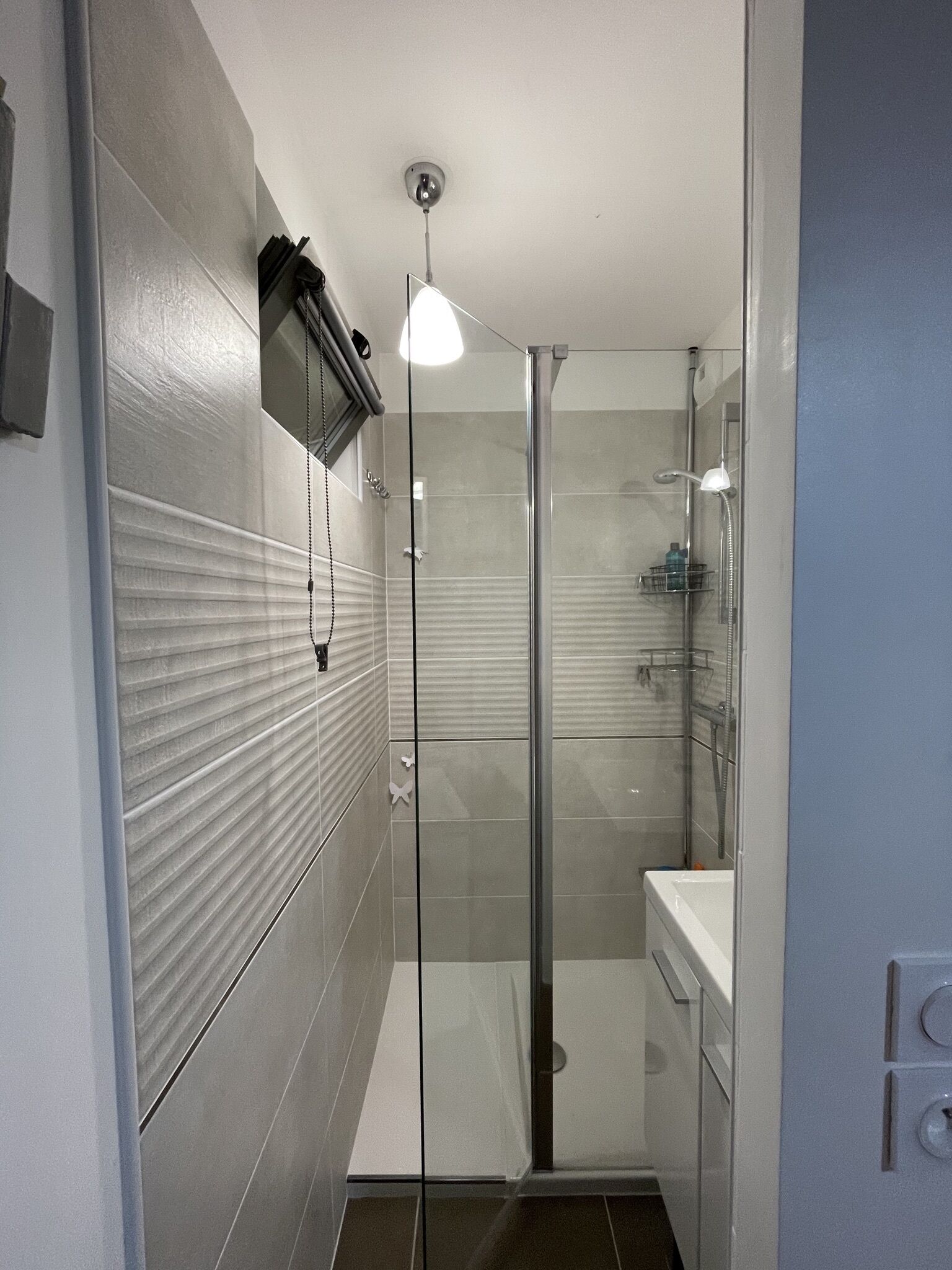 Une salle de bain moderne dotée d’une douche à parois de verre, d’un lavabo intégré et d’un porte-serviettes.