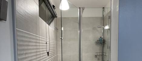 Une salle de bain moderne dotée d’une douche à parois de verre, d’un lavabo intégré et d’un porte-serviettes.
