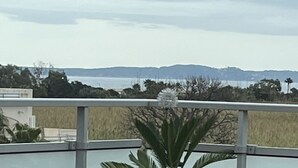 Un balcón con vista al mar y colinas lejanas.