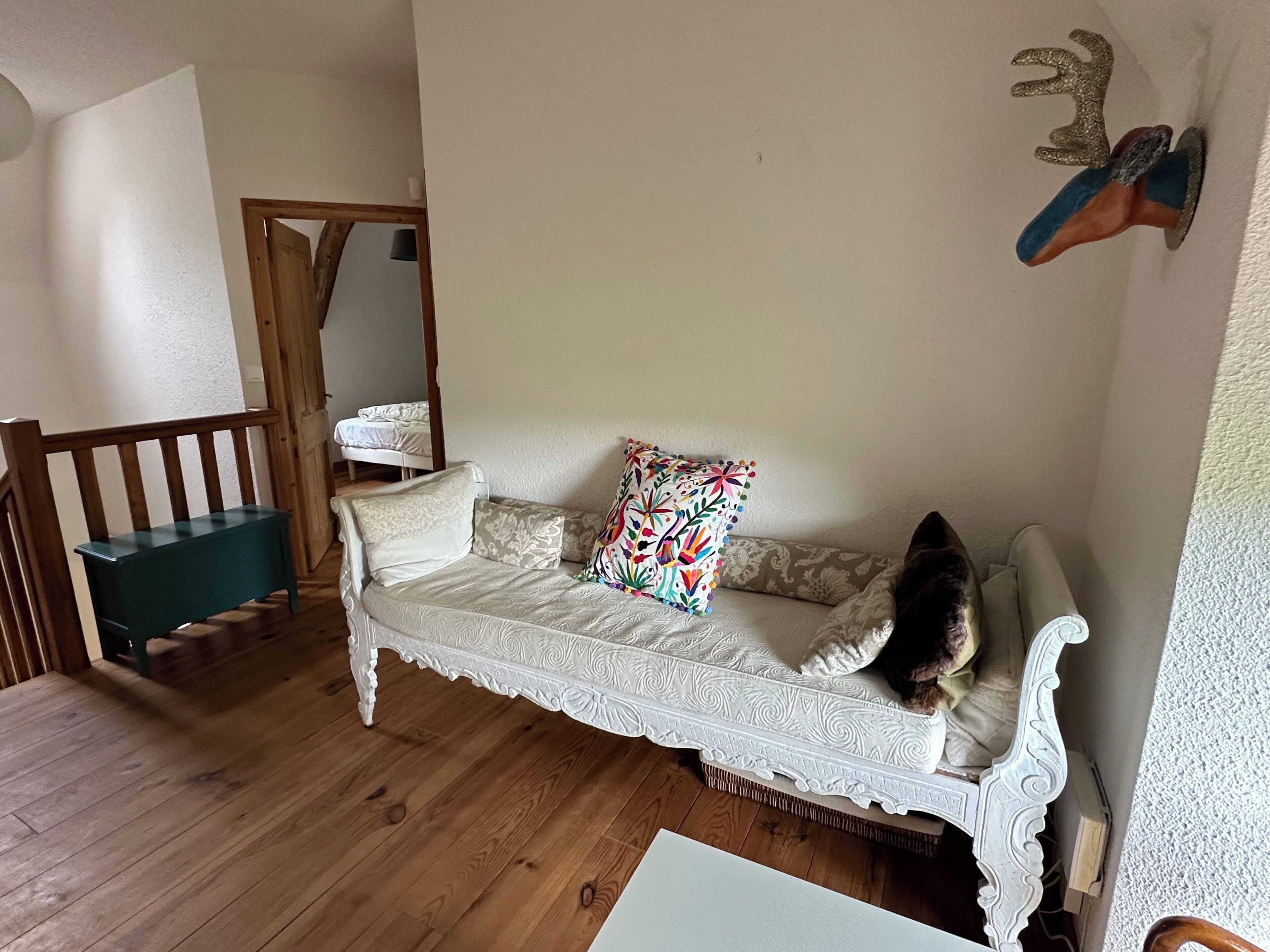 Une pièce chaleureuse avec un canapé blanc orné, un banc en bois et un coussin coloré.