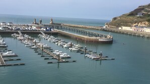 Ein Yachthafen mit angestaubten Booten, eine Pier, die sich ins Wasser erstreckt, und Gebäude im Hintergrund.