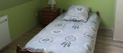 Een kleine kamer met een enkel bed, schuine wand en dakraam.
