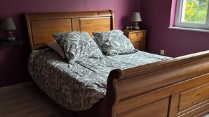 Ein Schlafzimmer mit einem hölzernen Bett, violetten Wänden und einem Fenster.