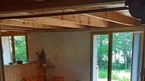 Ein gemütliches Zimmer mit Holzboden, einer Couch, einem Tisch und einem Fenster mit Blick auf Grünflächen.