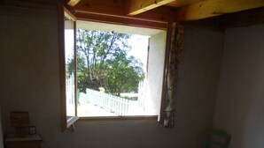 Ein Schlafzimmer mit Bett, Fenster, Stuhl und kleinem Tisch.