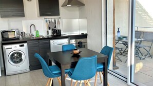 A modern kitchen with a dining area, a washing machine, and a large sliding glass door leading to an outdoor patio. - Apartment T2.40 m2, air-conditioned, 3 terraces, 350 m from the beach. Private parking. (Saint-Cyr-sur-Mer)