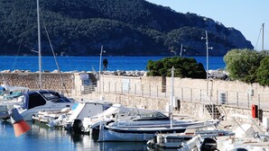 A marina with boats docked, a stone wall, and a mountainous backdrop. - Apartment T2.40 m2, air-conditioned, 3 terraces, 350 m from the beach. Private parking. (Saint-Cyr-sur-Mer)