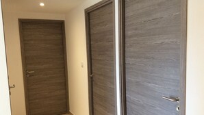 A hallway with two wooden doors, one with a handle and one with a push bar, leading to a room. - Very recent 3-room apartment in PORTICCIO - Sea view - 4-minute walk from the sea. (Grosseto-Prugna)