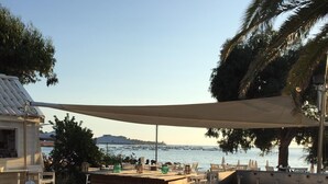 A wooden deck with outdoor seating, a bar area, and a view of the sea. - Very recent 3-room apartment in PORTICCIO - Sea view - 4-minute walk from the sea. (Grosseto-Prugna)