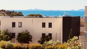 A modern building with a flat roof, multiple windows, and a view of the sea and mountains in the background. - Very recent 3-room apartment in PORTICCIO - Sea view - 4-minute walk from the sea. (Grosseto-Prugna)
