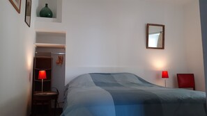 Ett sovrum med en säng, två sänglampor, en spegel, en garderob och ett litet bord med en lampa.
