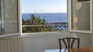 A corner room with a view of the sea, a wooden table, and two chairs.