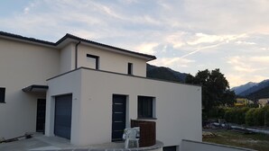 Ein modernes, zweistöckiges Gebäude mit Flachdach, Garage und kleiner Außenbereicherung mit Stuhl und Tisch.