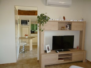 Ein Wohnzimmer mit Fernseher, einer Holzeinrichtungsanlage und einem Essbereich mit Tisch und Stühlen.