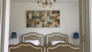 A bedroom with two beds, a chandelier, and a wall art piece. - La Futaie de Chabrehez  (Les Tailles)
