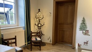 A room with a wooden door, a radiator, a table, and a chair. - La Futaie de Chabrehez  (Les Tailles)