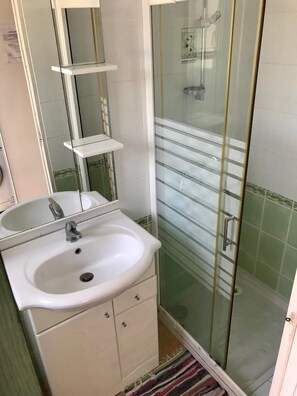 A bathroom with a white sink, mirror, and glass-enclosed shower.