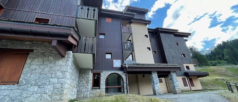 A multi-story building with a stone facade, wooden balconies, and a clear sky.