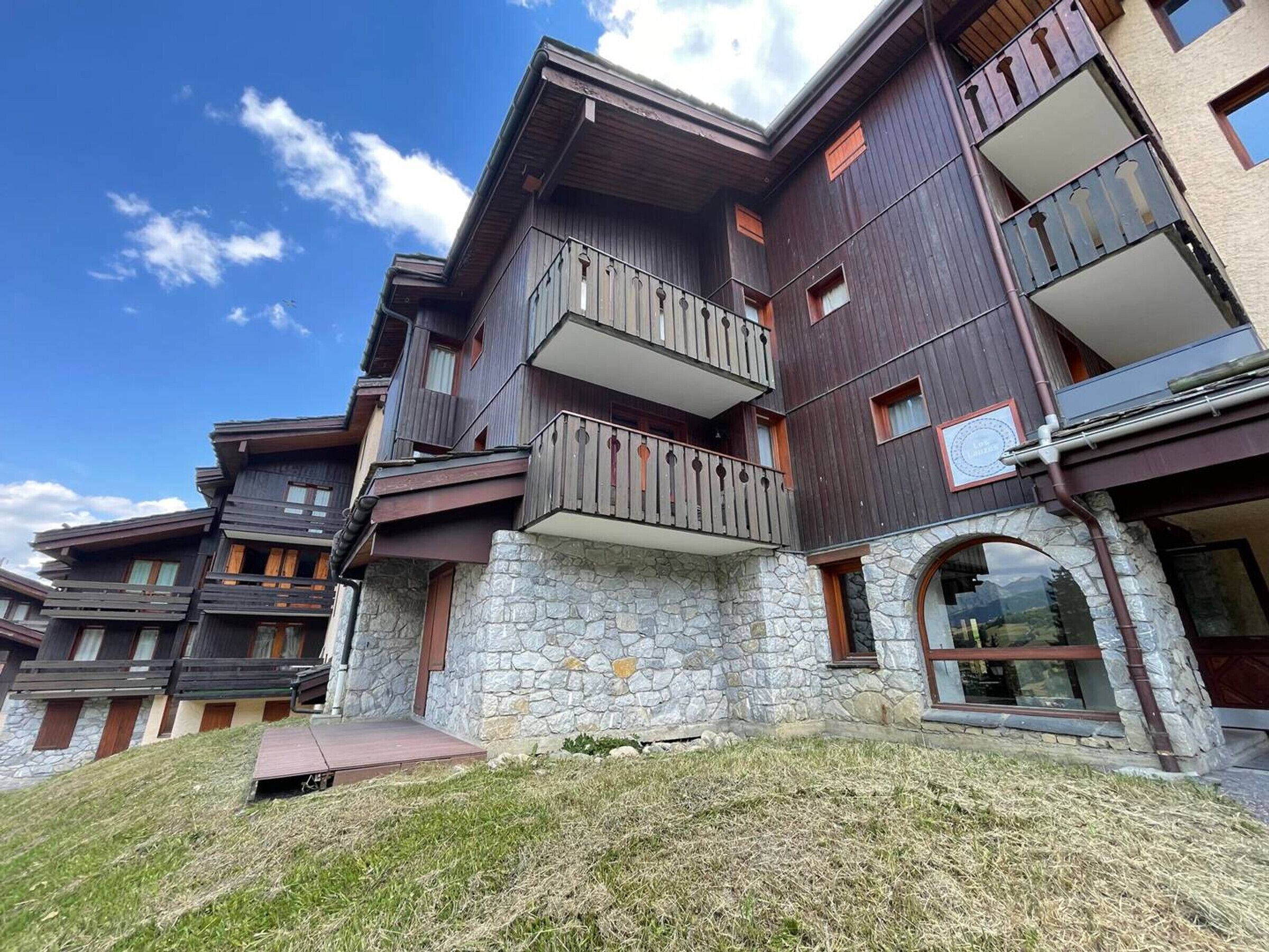 A multi-story building with balconies, stone facade, and a clear sky.