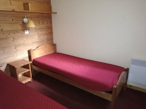 A small, single-bed room with a wooden headboard, a bedside table, a lamp, and a radiator. - 2-Room Ski-In/Ski-Out Apartment with Balcony, Near Pierrafort Gondola (Les Avanchers-Valmorel)