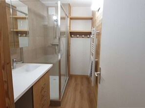 A bathroom with a glass shower enclosure, a white sink, wooden cabinets, and a towel rack. - 2-Room Ski-In/Ski-Out Apartment with Balcony, Near Pierrafort Gondola (Les Avanchers-Valmorel)
