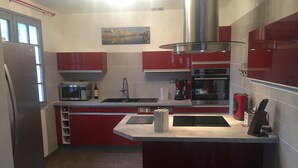 A modern kitchen with red cabinets, stainless steel appliances, and a large island.