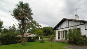 A house with a white exterior and dark trim, surrounded by a well-maintained lawn and various plants.