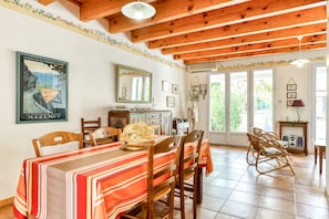 Un comedor con una mesa de madera, mantel a rayas y sillas de mimbre.