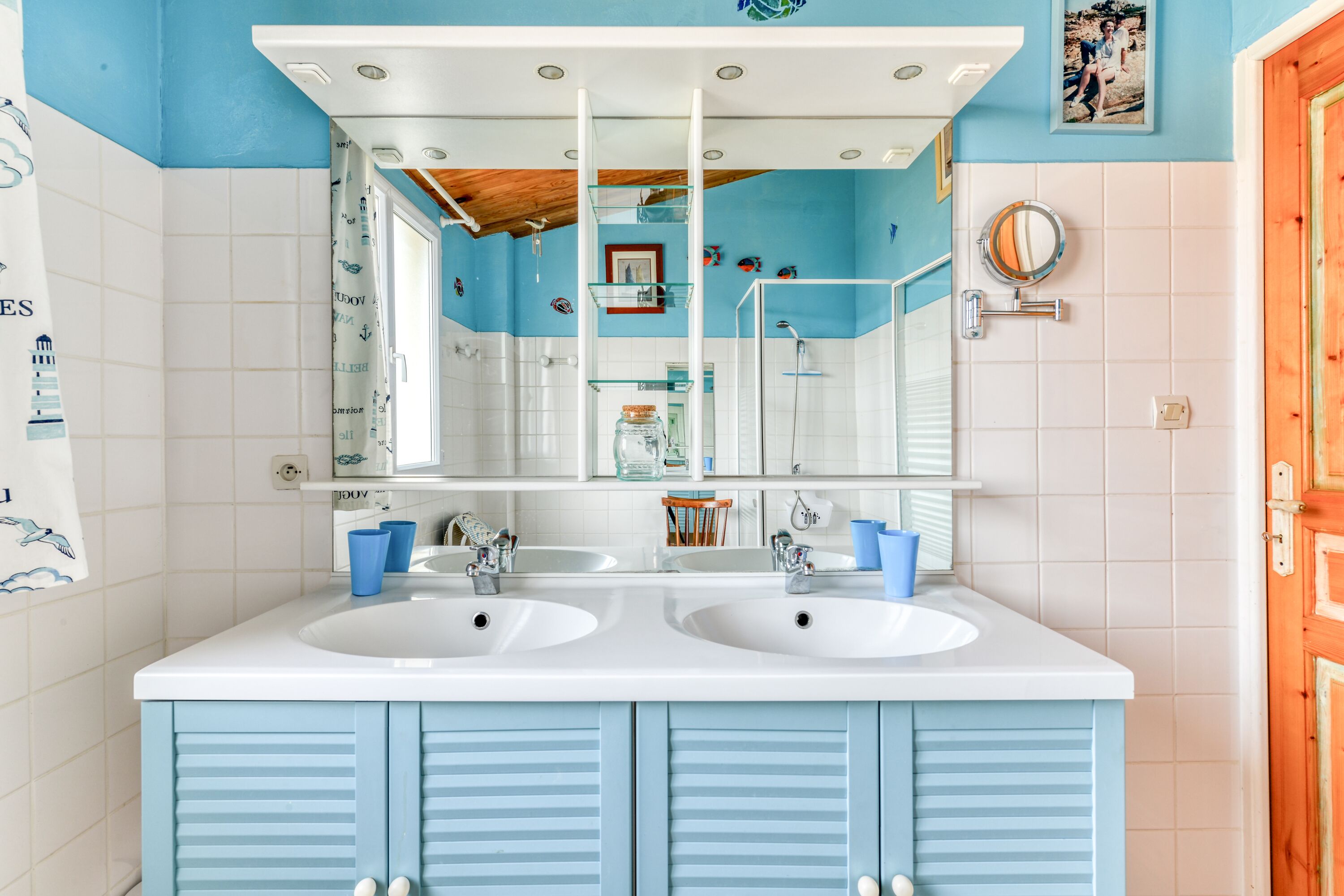 Een badkamer met twee wasbakken, een grote spiegel en een douche.