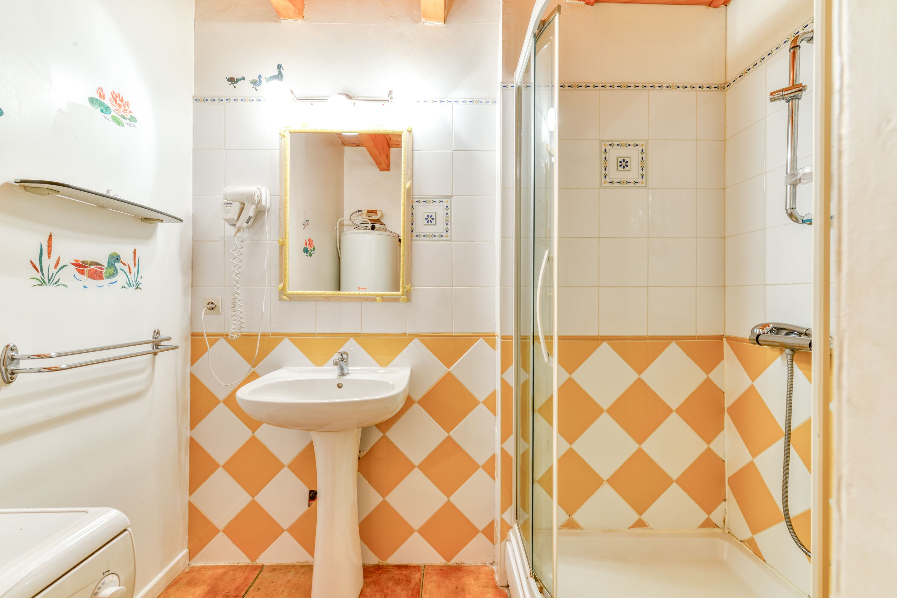 A bathroom with a sink, mirror, and shower.