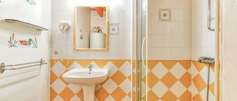 A bathroom with a sink, mirror, and shower.