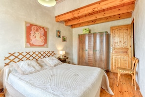 Un dormitorio con una cama grande, cabecera de madera, un armario y una silla.