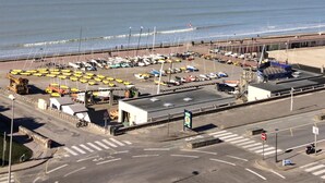 Ein Küstenhafen mit vertäuten Booten, eine Straße mit Verkehrsschildern und freie Sicht auf den Ozean.