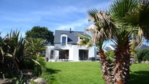 A modern house with a white exterior, a well-maintained lawn, and a palm tree in the foreground.
