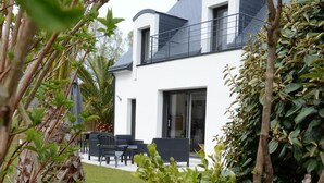 A modern house with a white exterior, a black roof, and a balcony.