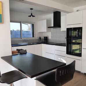 Una cocina moderna con encimera negra, armarios blancos, horno empotrado y ventana.