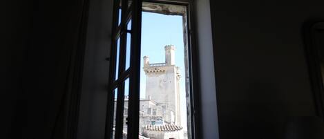 A window with a view of a tall tower with a spire.