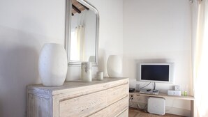 A wooden dresser with a mirror, two vases, and a flat-screen TV on a stand. - Magnificent Apartment in the heart of Uzès (Uzès)