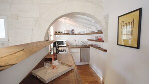 A compact kitchen with a wooden countertop, a wine glass tray, and a framed sign on the wall. - Magnificent Apartment in the heart of Uzès (Uzès)