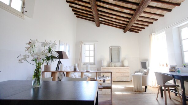 A spacious room with a wooden ceiling, a dining table, a white sofa, and a dresser. - Magnificent Apartment in the heart of Uzès (Uzès)